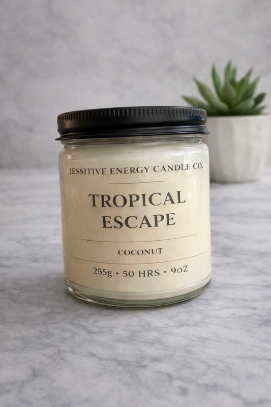 Candle jar labeled 'Tropical Escape' on a gray surface with a plant in the background