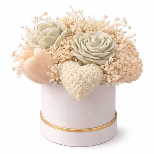 Decorative flower arrangement in a white container with gold rim on a white background