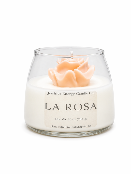 Candle in a glass jar labeled 'La Rosa' by Jessitive Energy Candle Co. on a white background